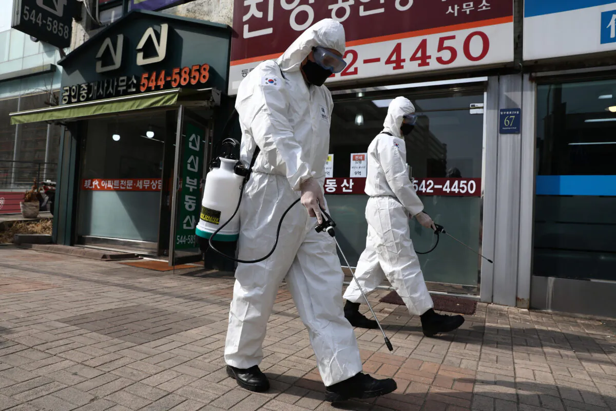 South Korean soldiers wear protective gear as they spray antiseptic solution to guard against the CCP virus along a street in Gangnam district in Seoul, South Korea, on March 9, 2020. (Chung Sung-Jun/Getty Images)