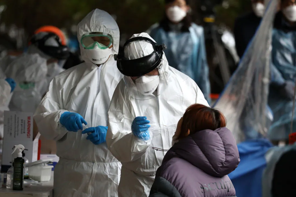 Medical staff wearing protective gear, take samples from people at a building where 46 people were confirmed to have the novel coronavirus, at a temporary test facility in Seoul on March 10, 2020. (Chung Sung-Jun/Getty Images)