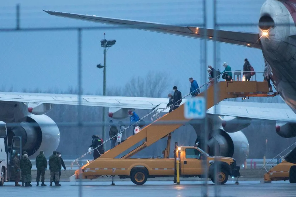 Passengers step off a plane carrying Canadians back from Oakland, Calif. from the Grand Princess cruise ship, after it arrived at Canadian Forces Base Trenton in Trenton, Ont., on March 10, 2020. (The Canadian Press/Lars Hagberg)