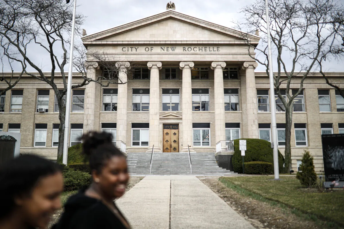 Pedestrians pass New Rochelle City Hall, in New York on March 10, 2020. (John Minchillo/AP Photo)