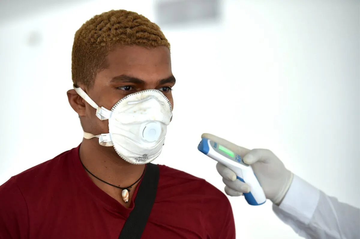 A security member checks the temperature of a passenger as a preventive measure against the spread of the new coronavirus at the Bonilla Aragon international airport in Palmira, Colombia, on March 10, 2020. (Luis Robayo/AFP via Getty Images)