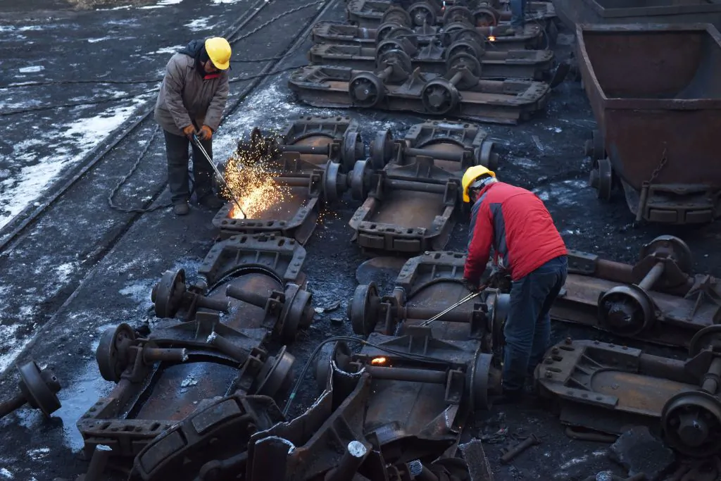 Workers cut up coal carts at the Datai coal mine in Mentougou, west of Beijing, on Dec. 18, 2019. (Greg BakerAFP via Getty Images)