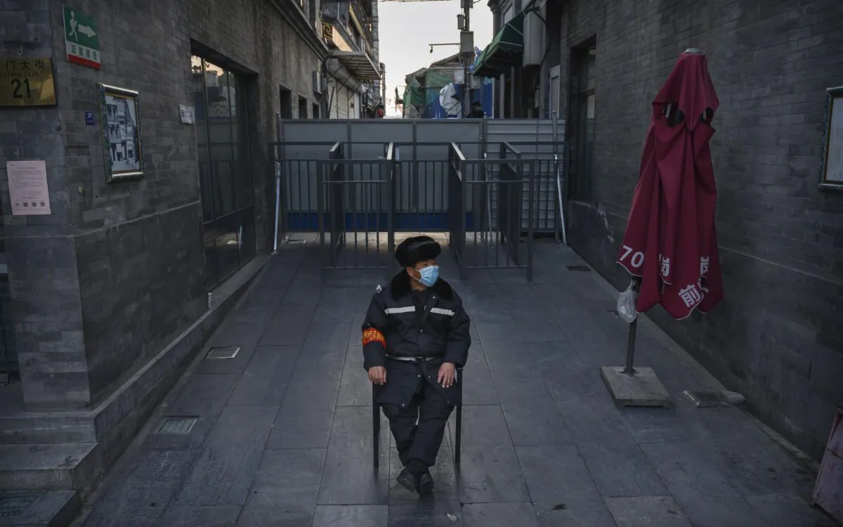 A Chinese guard wears a face mask as he watches an area near a barricade blocking a residential community from a commercial area in Beijing on March 11, 2020. (Kevin Frayer/Getty Images)