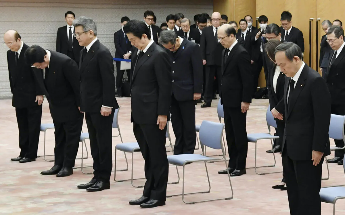 Japanese Prime Minister Shinzo Abe, center, observes a moment of silence at 2:46 p.m. when a magnitude 9.0 earthquake struck off Japan's northeastern coast nine years ago, at the prime minister's office in Tokyo on Wednesday, March 11, 2020. (Yoshitaka Sugawara/Kyodo News via AP)