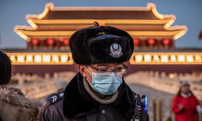 A police officer wearing a protective mask walks past the portrait of late communist leader Mao Zedong (not pictured) at Tiananmen Gate in Beijing on Jan. 23, 2020. (NICOLAS ASFOURI/AFP via Getty Images)