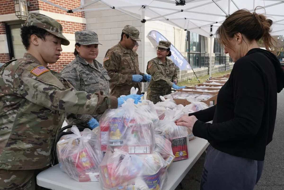 National Guard troops give food to residents of New Rochelle, New York, at New Rochelle High School March 12, 2020. The National Guard is helping to clean surfaces and deliver food in the one-mile radius containment area around a point near a synagogue connected to some existing cases of what appears to be the nation’s biggest cluster of cases of COVID-19. (TIMOTHY A. CLARY/AFP via Getty Images)