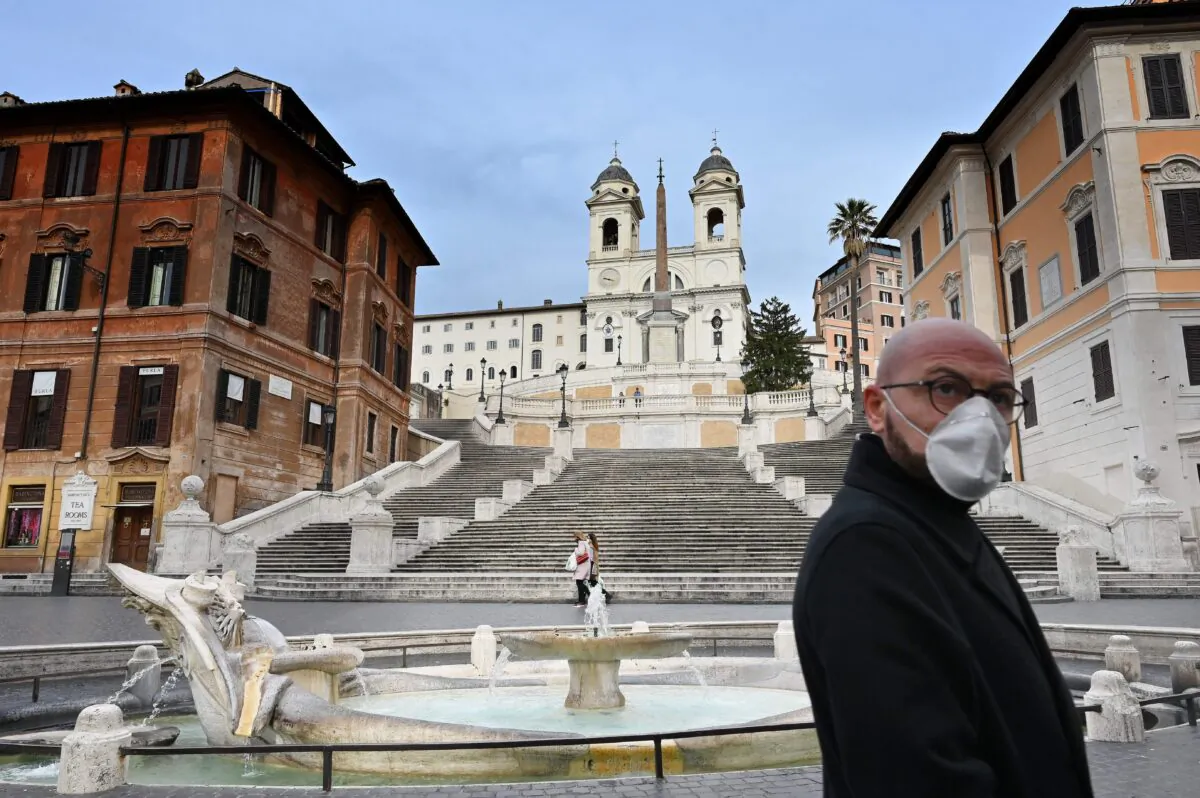 A man wearing a protective mask walks by a deserted Piazza di Spagna in central Rome, Italy, on March 12, 2020. (Alberto Pizzoli/AFP via Getty Images)