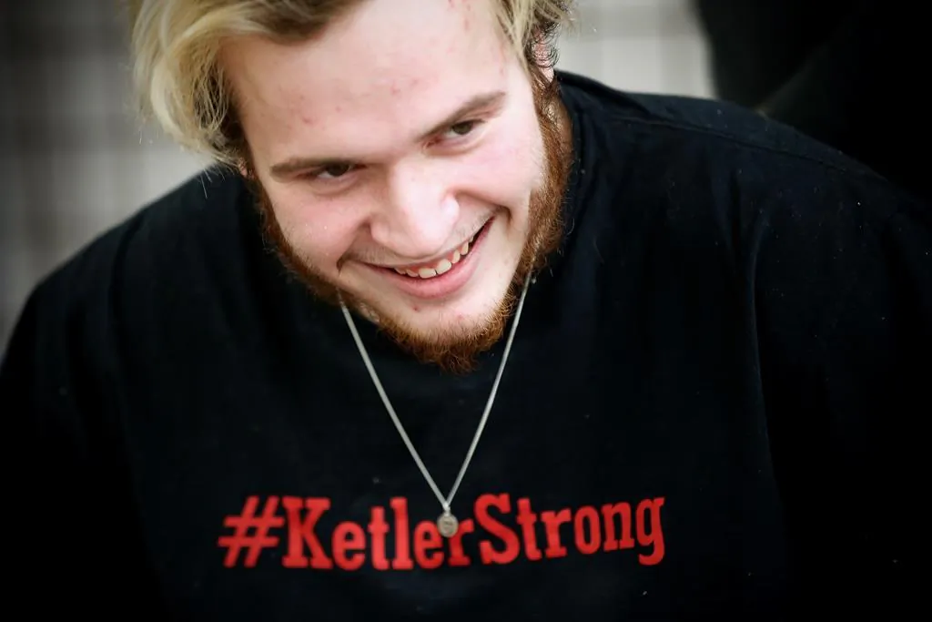 Reese Ketler, a 19-year-old who was paralyzed during a hockey game in December, wears a necklace with his jersey number and a t-shirt with his hashtag as works through his rehabilitation with physiotherapist Kevin Stewart at the Health Sciences Centre in Winnipeg, on March 5, 2020. (John Woods/The Canadian Press)