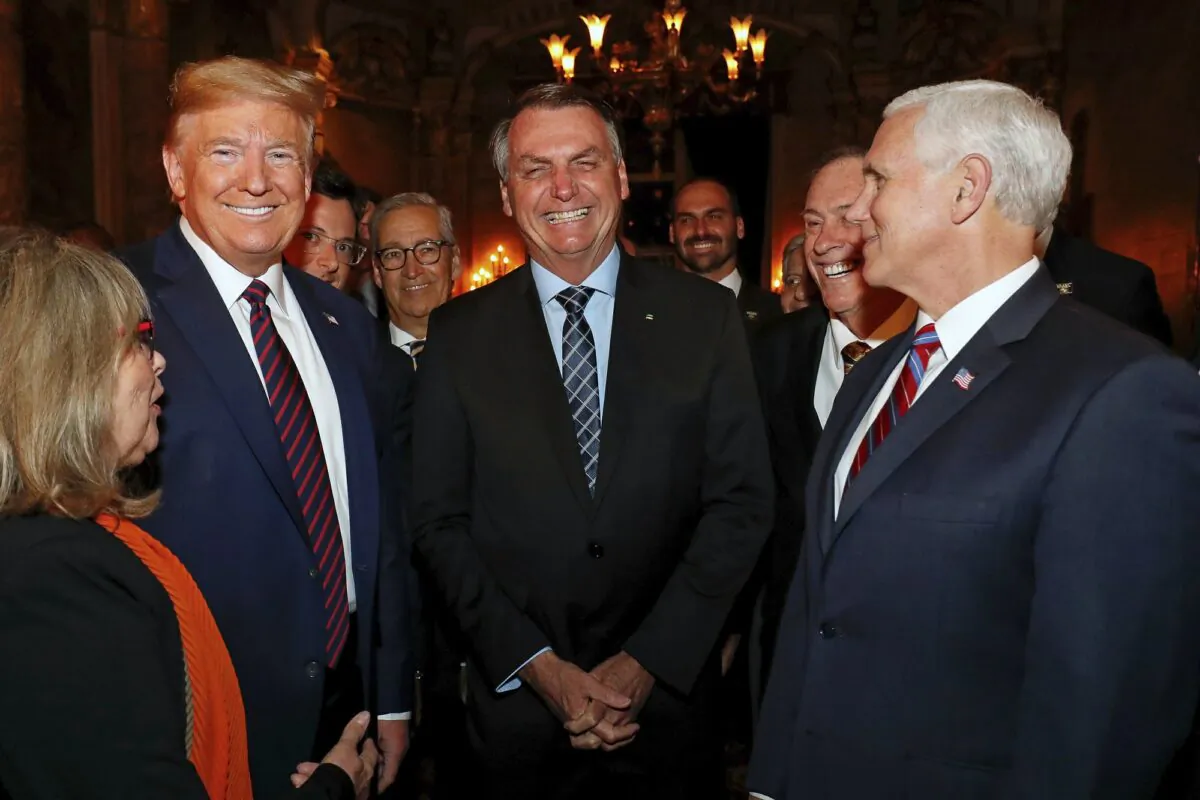 Brazil's presidential press office, Brazil's President Jair Bolsonaro, center, stands with President Donald Trump, second from left, Vice President Mike Pence, right, and Brazil's Communications Director Fabio Wajngarten, behind Trump partially covered, during a dinner in Florida on March 7, 2020. (Alan Santos/Brazil's Presidential Press Office via AP)