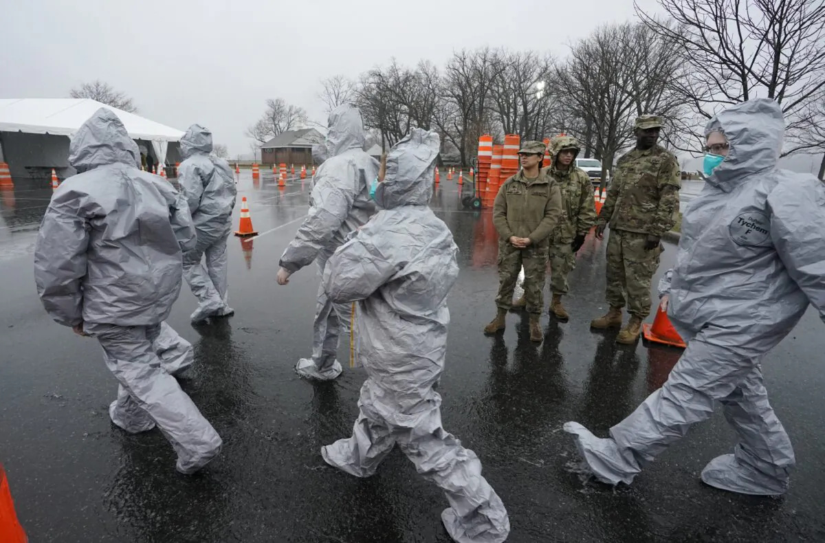 Workers in protective suits get ready while waiting for people to be tested as they arrive by car at the state's first drive through COVID-19 Mobile Testing Center at Glen Island Park in New Rochelle, New York, on March 13, 2020. (Timothy A. Clary/AFP via Getty Images)