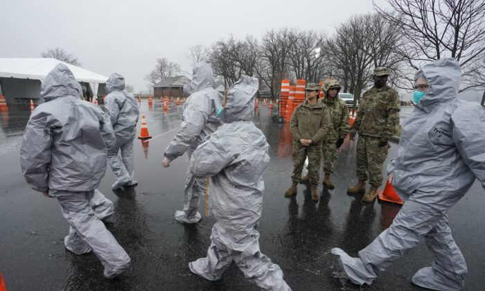 Workers in protective suits get ready while waiting for people to be tested as they arrive by car at the state's first drive through COVID-19 Mobile Testing Center at Glen Island Park in New Rochelle, New York, on March 13, 2020. (Timothy A. Clary/AFP via Getty Images)