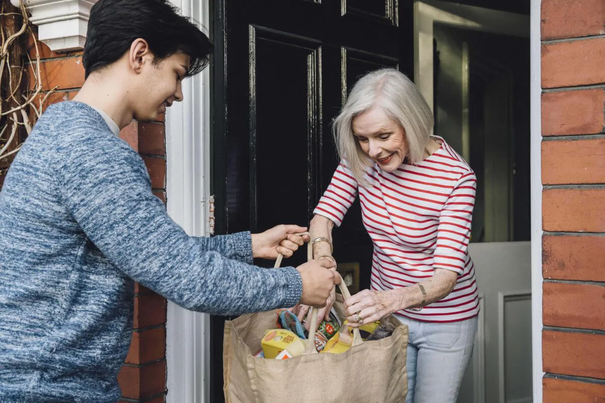 A young man delivers groceries to a woman at her home in a file photo. (DGLimages/Shutterstock)