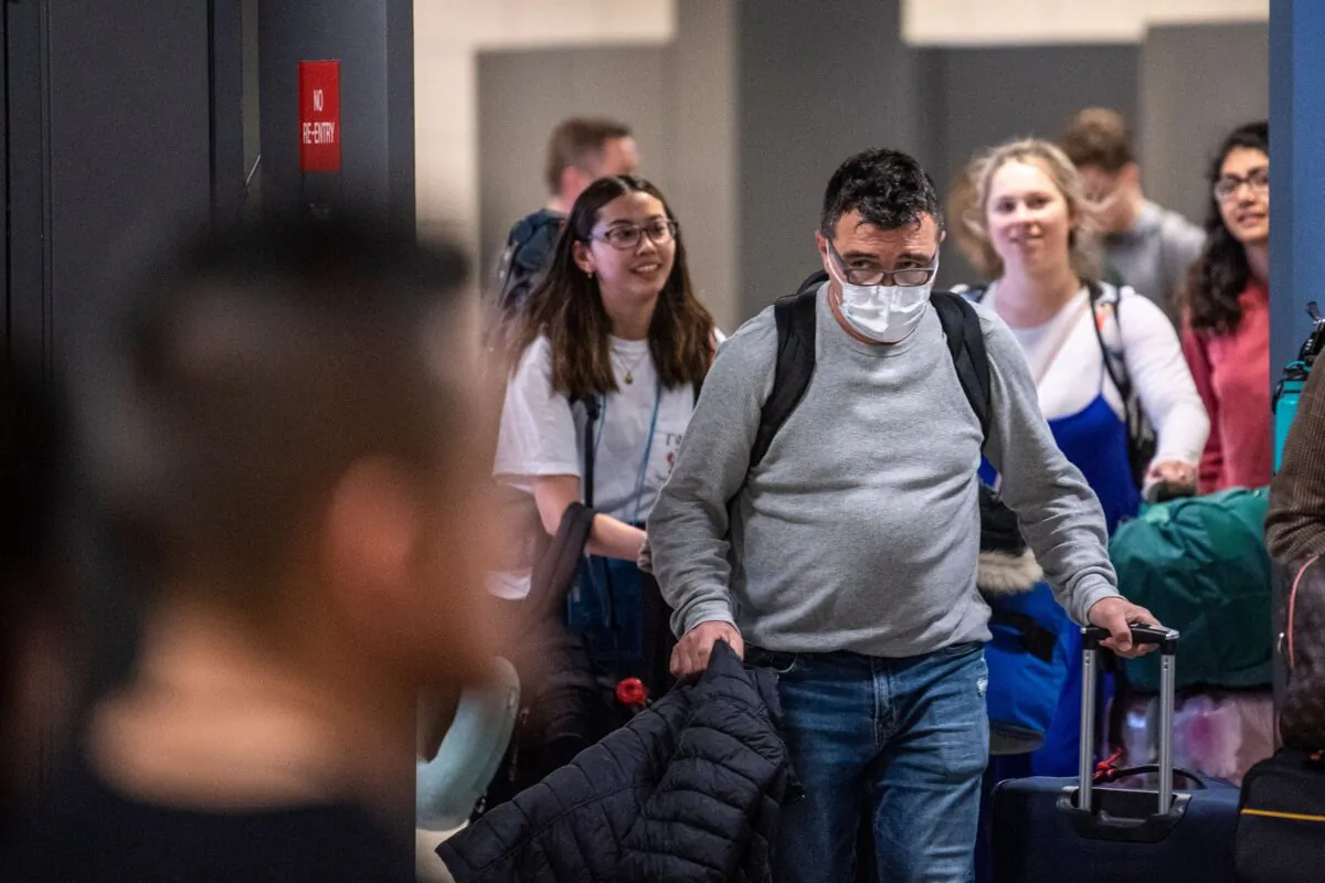 A passenger arriving from Brussels wearing a mask to protect himself from the new coronavirus looks for his relatives in the International arrivals zone at Dulles Airport outside Washington on March 13, 2020. (Eric Baradat/AFP via Getty Images)