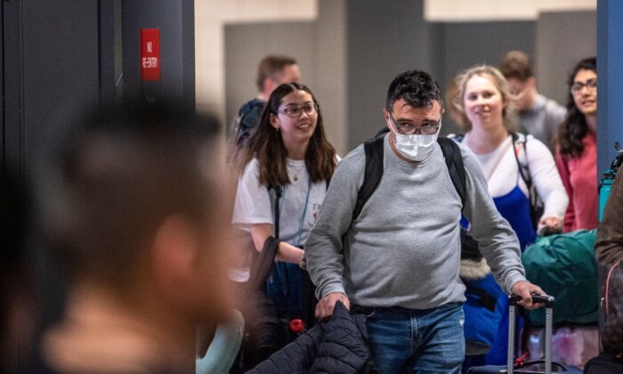 A passenger arriving from Brussels wearing a mask to protect himself from the new coronavirus looks for his relatives in the International arrivals zone at Dulles Airport outside Washington on March 13, 2020. (Eric Baradat/AFP via Getty Images)