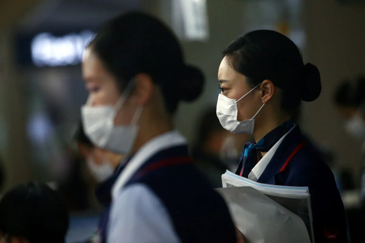 Employes wearing protective masks following the outbreak of the coronavirus disease (COVID-19) are pictured at the Kansai International Airport in Osaka, Japan, on March 14, 2020. (Edgard Garrido/Reuters)