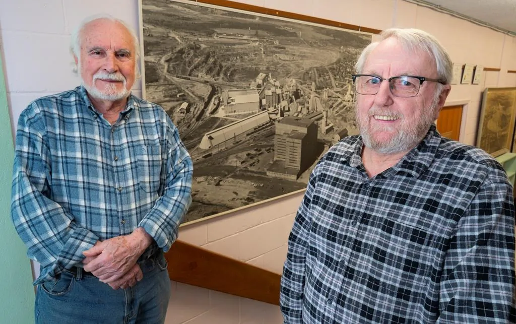 Francesco Spertini (L) and Mario Leblanc are seen in front of a historical picture of the open pit mine in Asbestos, Que., on March 11, 2020. (Paul Chiasson/The Canadian Press)