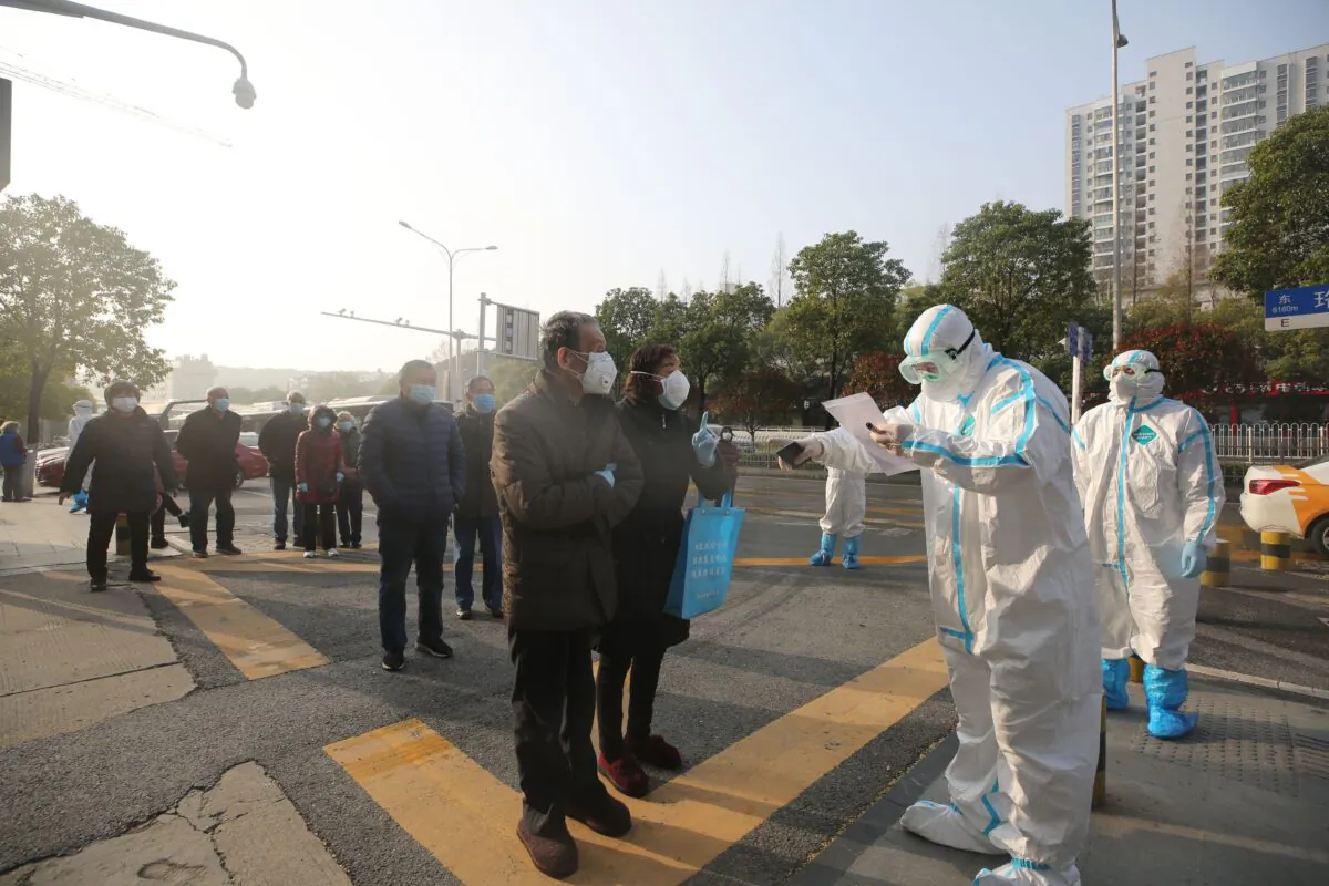 Medical workers dressed in protective suits check patients who recovered from COVID-19 as they arrive to be tested again at a hospital in Wuhan on March 14, 2020. (STR/AFP via Getty Images)