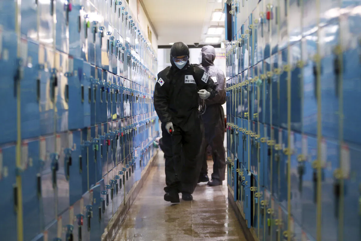 A South Korean army soldier wearing a protective suit sprays disinfectant as a precaution against the new coronavirus at a private academy in Daegu, South Korea, on March 15, 2020. (Kim Hyun-tae/Yonhap via AP)