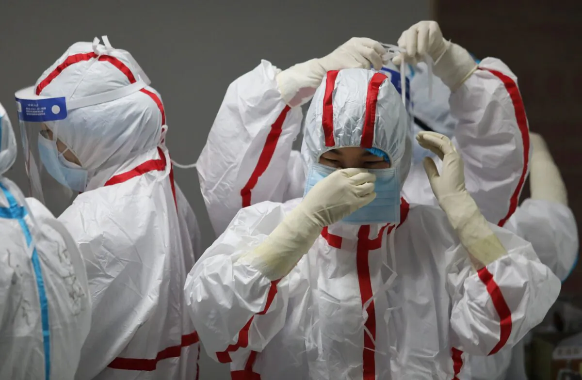 Medical staff put on protective equipment before attending to patients with COVID-19 at the Red Cross Hospital in Wuhan, China, on March 16, 2020. (STR/AFP via Getty Images)