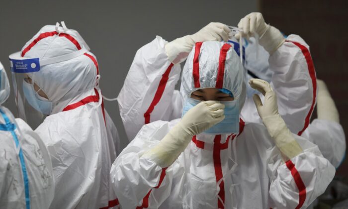 Medical staff put on protective equipment before attending to COVID-19 coronavirus patients at the Red Cross Hospital in Wuhan, China, on March 16, 2020. (STR/AFP via Getty Images)