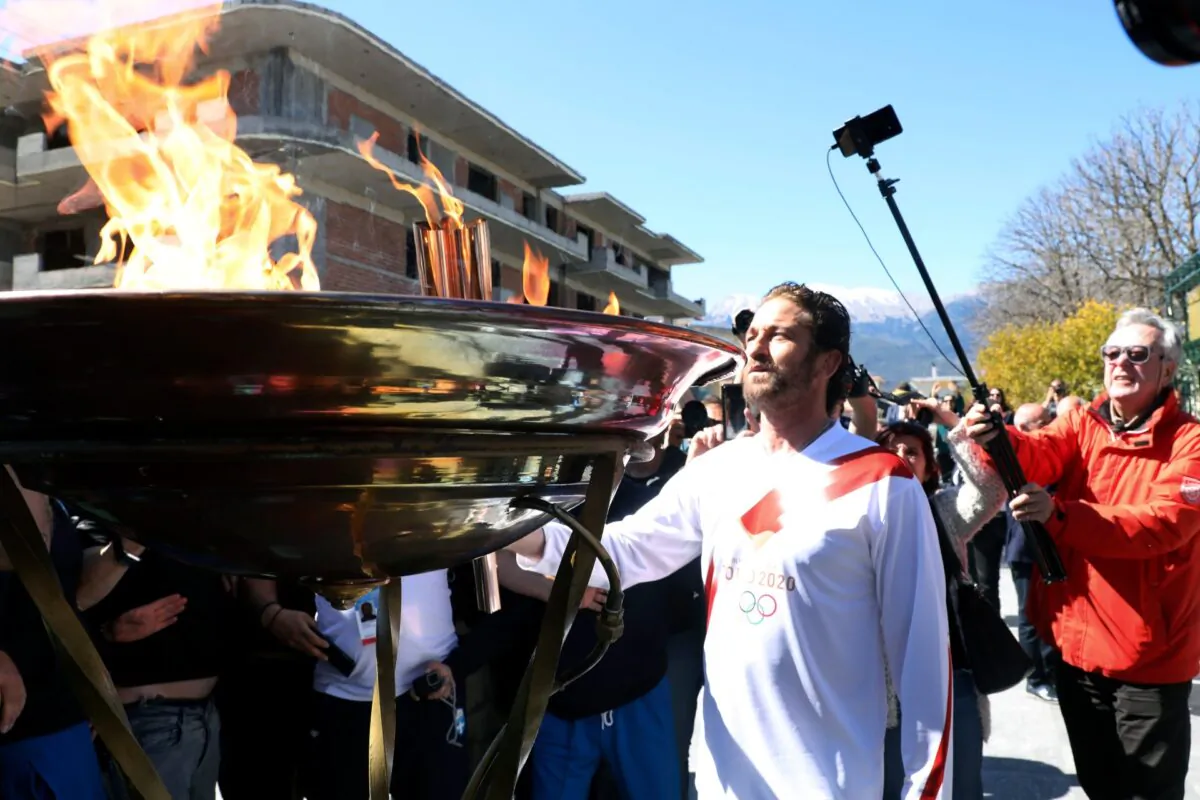 US actor Gerard Butler lights an altar as a torchbearer during the Olympic torch relay of the 2020 Tokyo Olympic Games in the southern Greek town of Sparta on March 13, 2020. (AP Photo)