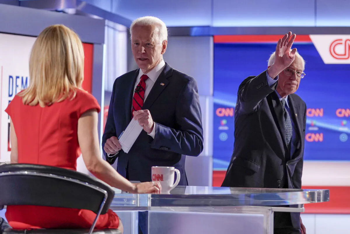 Former Vice President Joe Biden, center, stops to talk with CNN anchor Dana Bash, left, as Sen. Bernie Sanders (I-Vt.) right, waves after they participated in a Democratic presidential primary debate at CNN Studios in Washington on March 15, 2020. (Evan Vucci/AP Photo)