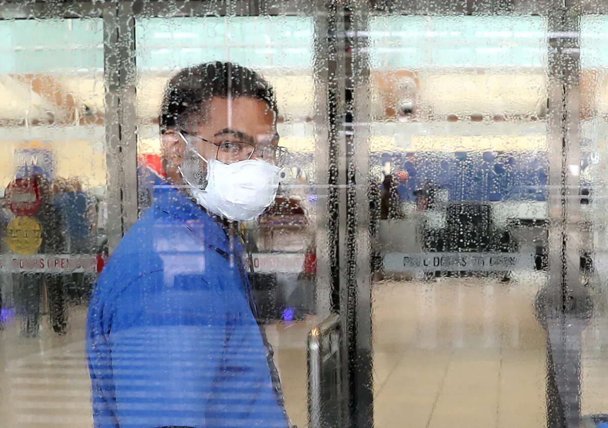 A worker at Baltimore/Washington International Thurgood Marshall Airport wears a mask as he cleans a glass door in Baltimore, Maryland on March 13, 2020. (Mark Wilson/Getty Images)