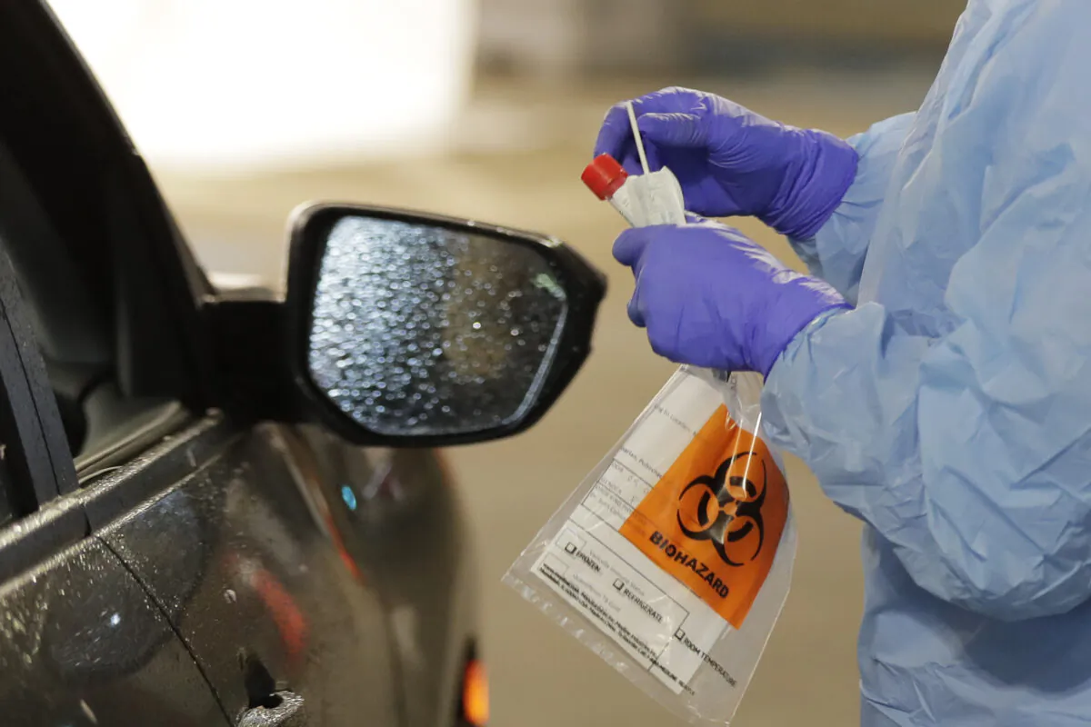 A nurse at a drive-thru coronavirus testing station, set up by the University of Washington Medical Center, holds a swab used to take a sample from the nose of a person in their car in Seattle, Washington, on March 13, 2020, (Ted S. Warren/AP Photo)
