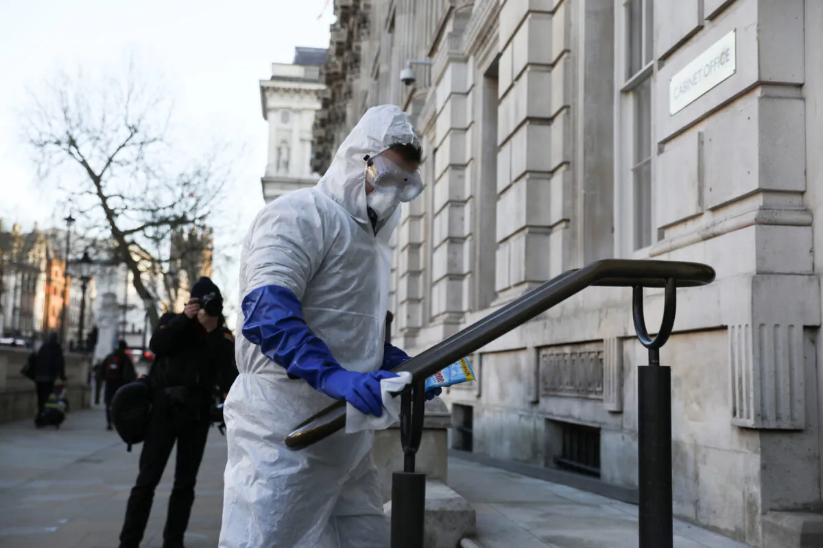 A man in a protective suit cleans a hand rail as the number of coronavirus cases (COVID-19) grows around the world, in London, Britain, on March 16, 2020. (Simon Dawson/Reuters)
