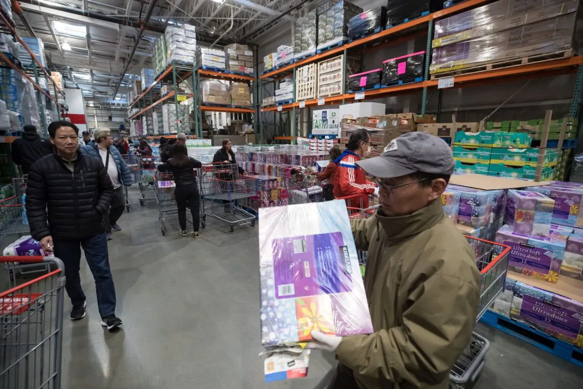 A man carries a multi-package of facial tissues while shopping along with hundreds of others who filled a Costco store in Burnaby, B.C., on the morning of March 16, 2020, amid concerns about the spread of the novel coronavirus. (The Canadian Press/Darryl Dyck)
