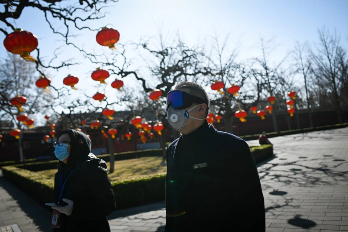 A park employee seen wearing goggles and mask walks in a park in Beijing, China, on March 14, 2020. (Wang Zhao/AFP via Getty Images)