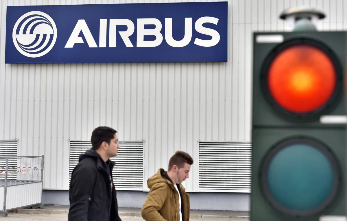 Men walk in front of a logo of the civil aircraft manufacturing company Airbus at the entrance of the Airbus facility in Bouguenais, western France, on March 20, 2017. (Loic Venance/AFP via Getty Images)
