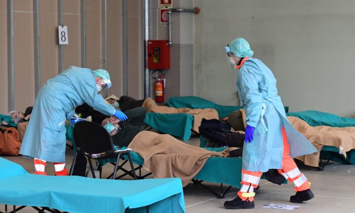 Hospital employees attend to a patient at a temporary emergency structure set up outside the emergency department at the Brescia Hospital in Lombardy, Italy, on March 13, 2020. (Miguel Medina/ AFP)