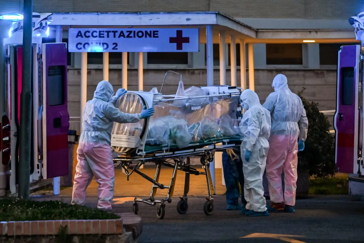 Medical workers in overalls stretch a patient under intensive care into the newly built Columbus Covid 2 temporary hospital to fight the new coronavirus infection, at the Gemelli hospital in Rome on March 16, 2020. (Andreas Solaro/AFP via Getty Images)