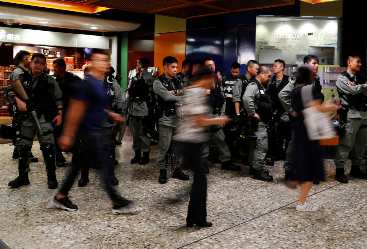 Riot police wait at a Mass Transit Railway (MTR) station as commuters walk past to catch a subway train, in Hong Kong, China, on Sept. 2, 2019. (Anushree Fadnavis/Reuters)