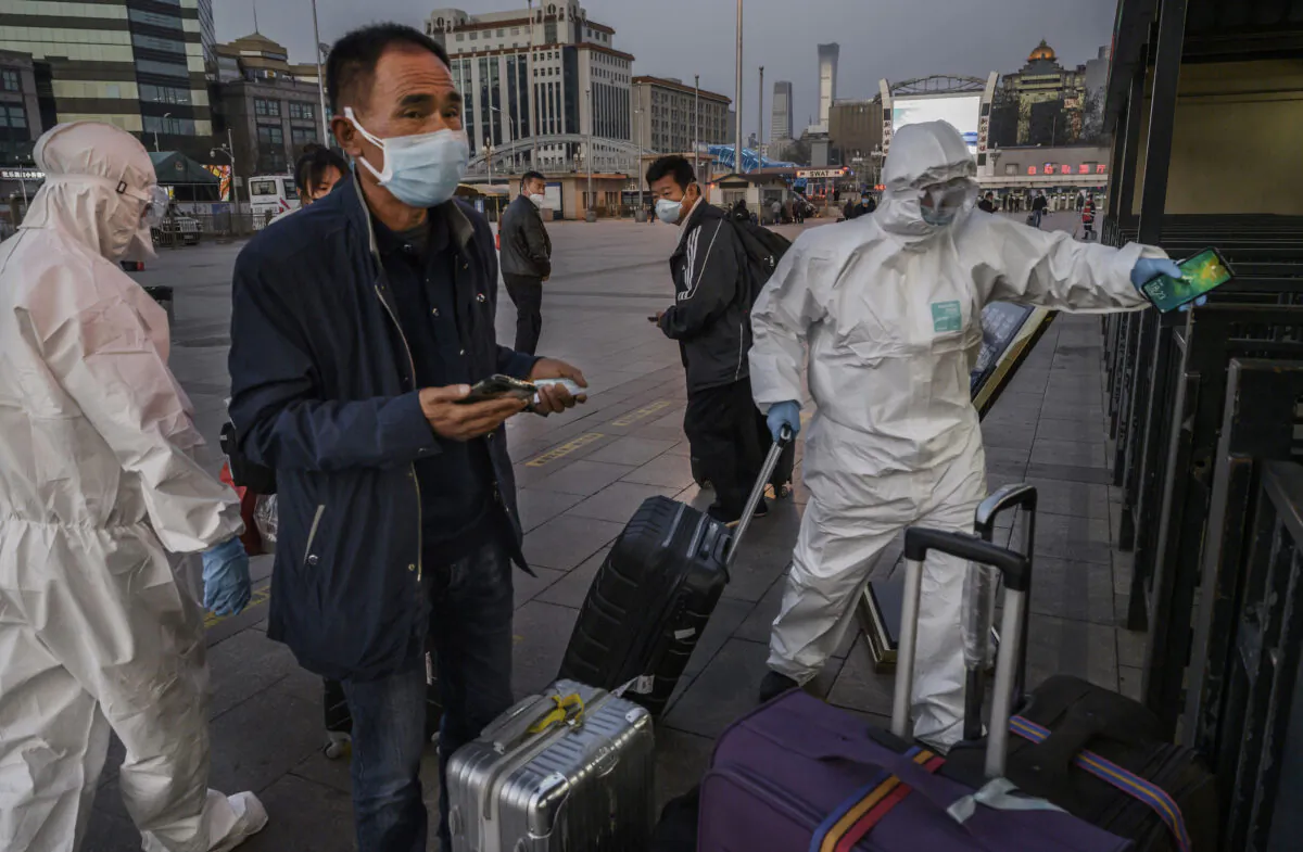 People wear protective masks and clothing as they arrive at Beijing Railway Station in Beijing, China, on March 13, 2020. (Kevin Frayer/Getty Images)