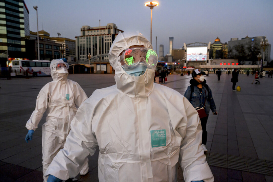 Two persons wearing protective masks and suits arrive at Beijing Railway Station on March 13, 2020. (Kevin Frayer/Getty Images)