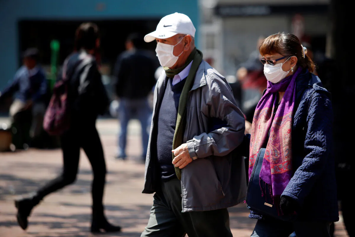 People walk on the street, wearing protective masks as a preventive measure against the spread of the coronavirus disease (COVID-19), in Bogota, Colombia March 17, 2020. (Reuters/Leonardo Munoz)