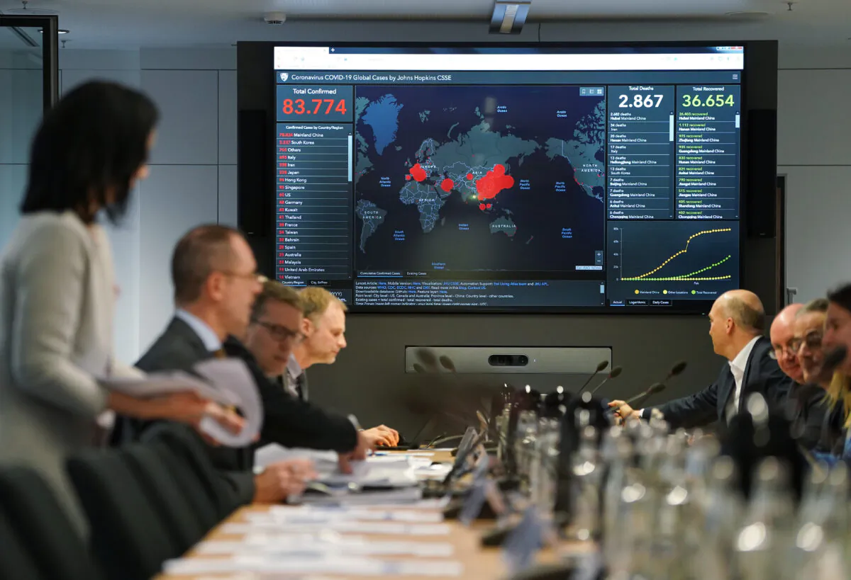 Members of Germany's coronavirus emergency task force sit down for a work session while a monitor shows the global spread and human toll of the virus at offices of the Ministry of Health on Feb. 28, 2020 in Berlin, Germany. (Sean Gallup/Getty Images)