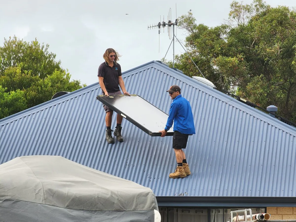 Two workers remove an old solar panel from a roof in Albany, Western Australia, on Feb. 17, 2025. (Susan Mortimer/The Epoch Times)