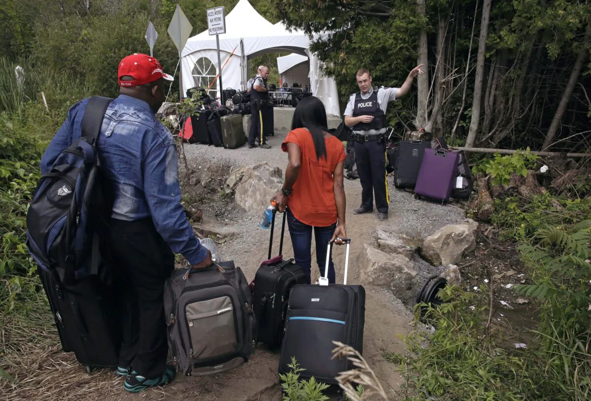 An RCMP officer informs a migrant couple of the location of a legal border station, shortly before they illegally crossed from Champlain, N.Y., to Saint-Bernard-de-Lacolle, Que., via Roxham Road. (AP Photo/Charles Krupa, File)