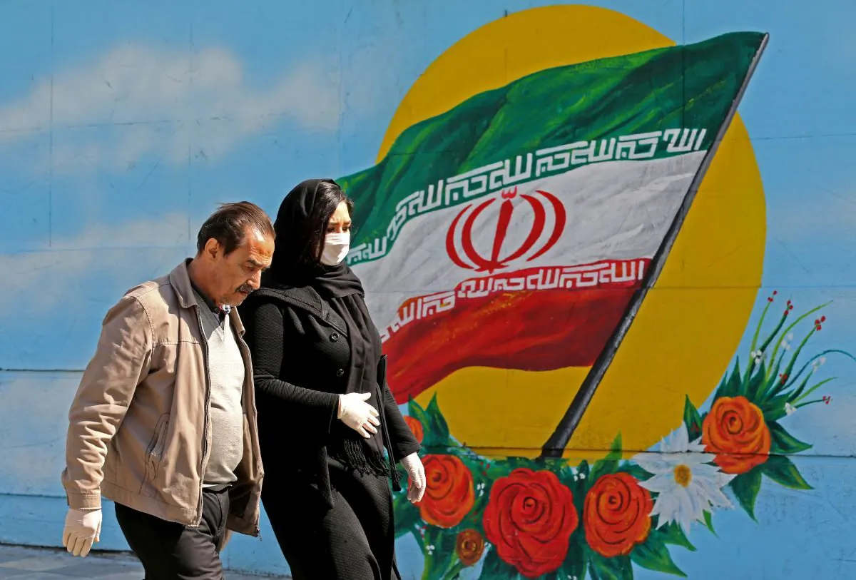 Iranians wearing masks walk past a mural displaying their national flag in Tehran on March 4, 2020. (Atta Kenare/AFP via Getty Images)