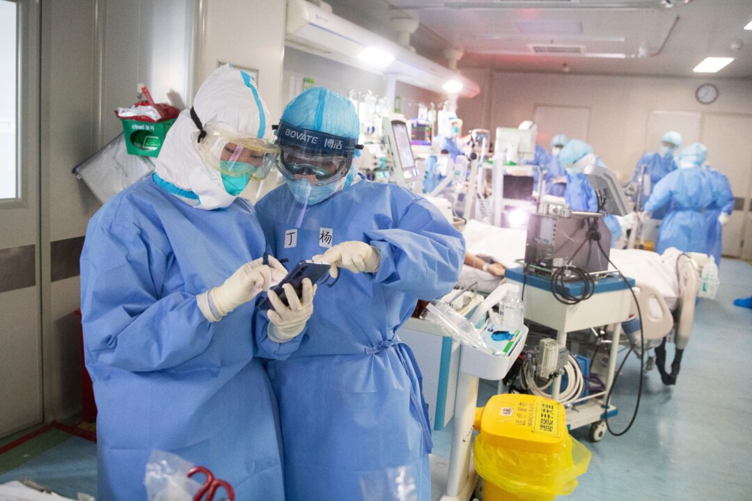Medical staff check a mobile phone as they treat CCP virus patients at a hospital in Wuhan, China, on March 19, 2020. (STR/AFP via Getty Images)