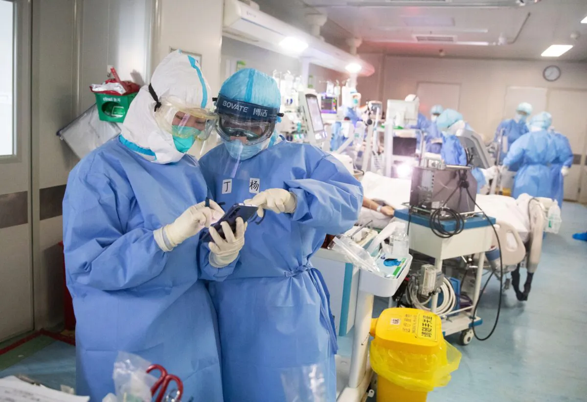 Medical staff check a mobile phone as they treat CCP virus patients at a hospital in Wuhan, China, on March 19, 2020. (STR/AFP via Getty Images)