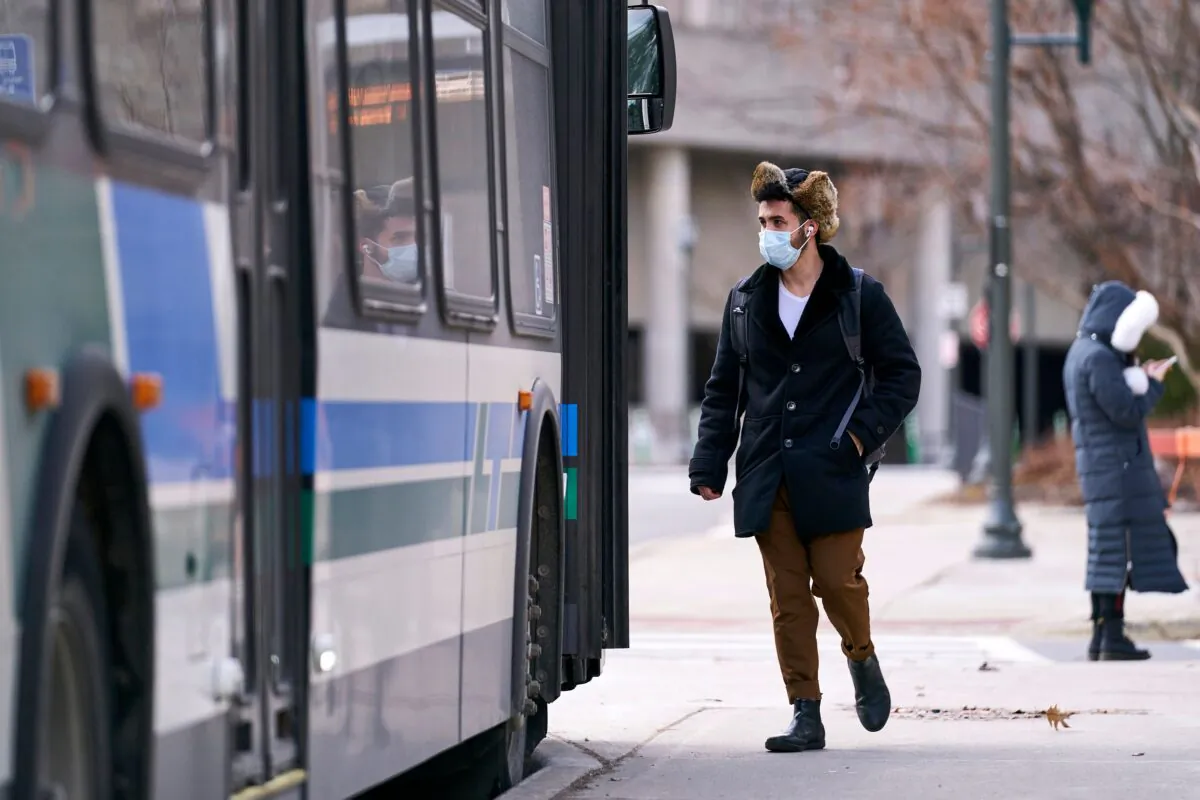A man in a mask boards a bus on campus at Western University in London, Ontario, on March 13, 2020. (Geoff Robins/AFP via Getty Images)