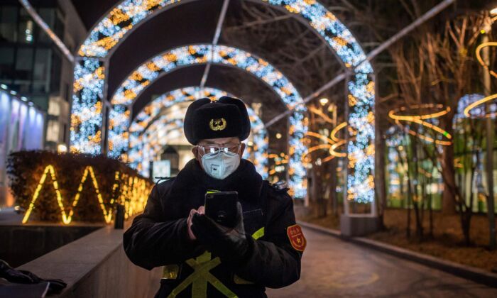 A security guard reads his cellphone while securing the entrance of a nearly empty shopping mall in Beijing, China, on Feb. 27, 2020. (NICOLAS ASFOURI/AFP via Getty Images)