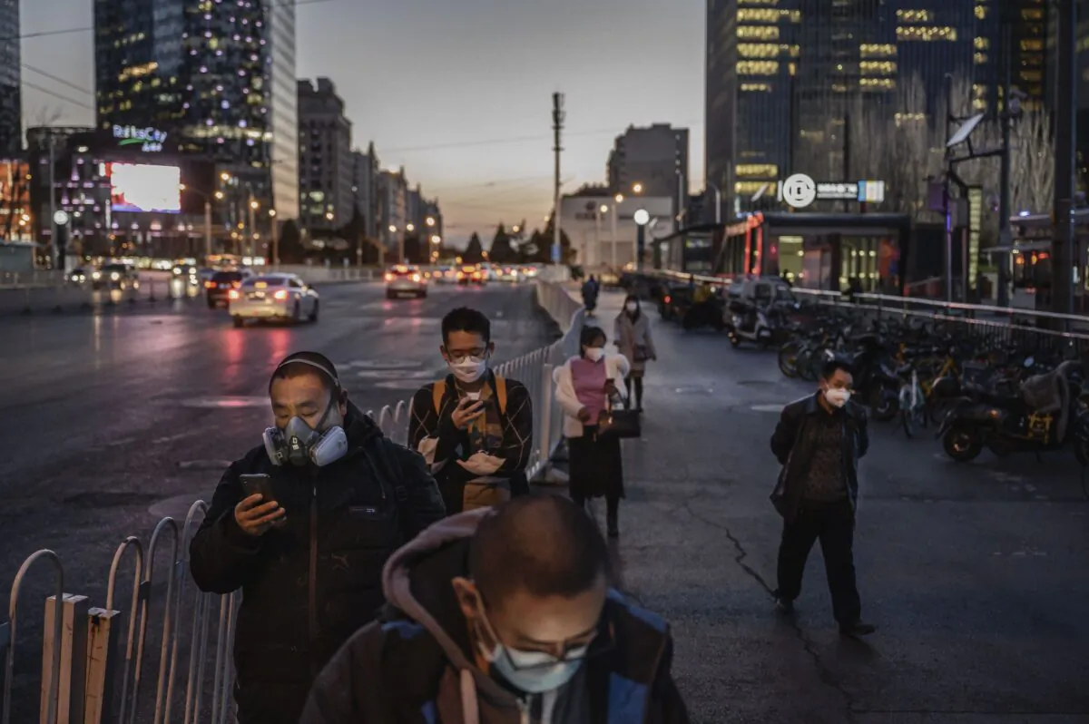 Chinese commuters wear protective masks as they line up to wait for a bus in Beijing on March 20, 2020.  (Kevin Frayer/Getty Images)