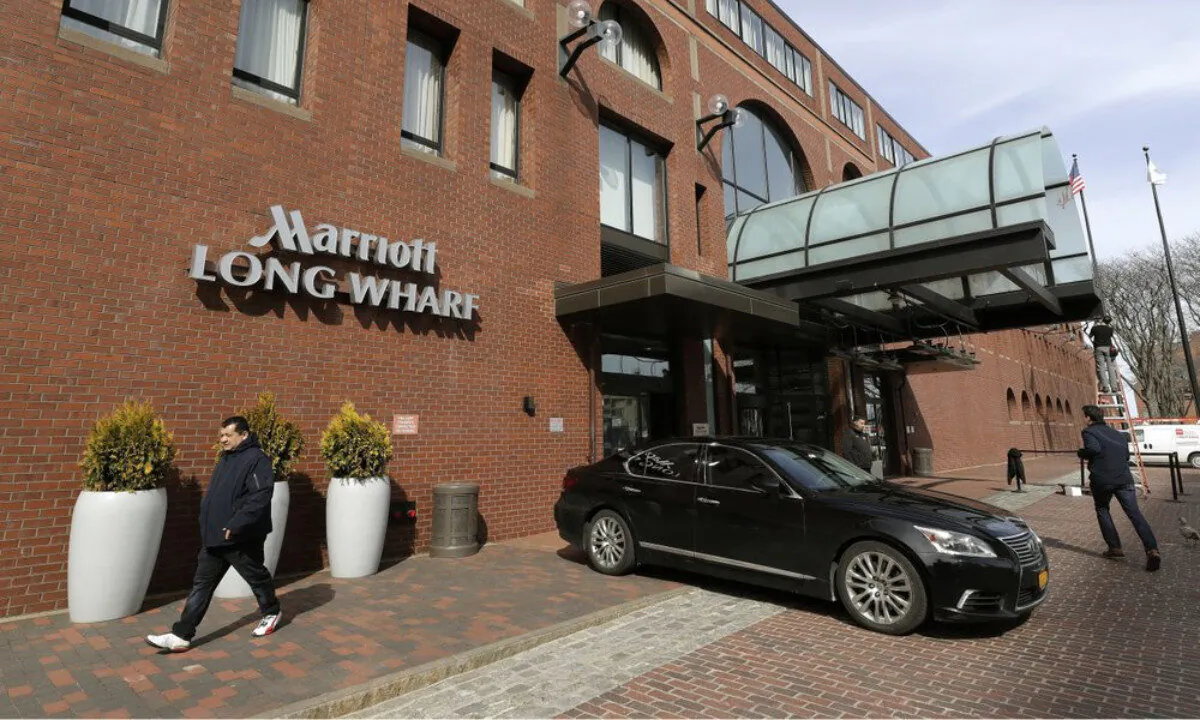 People walk outside the Marriott Long Wharf hotel in Boston, Massachusetts, on March 11, 2020. (Steven Senne/AP Photo)
