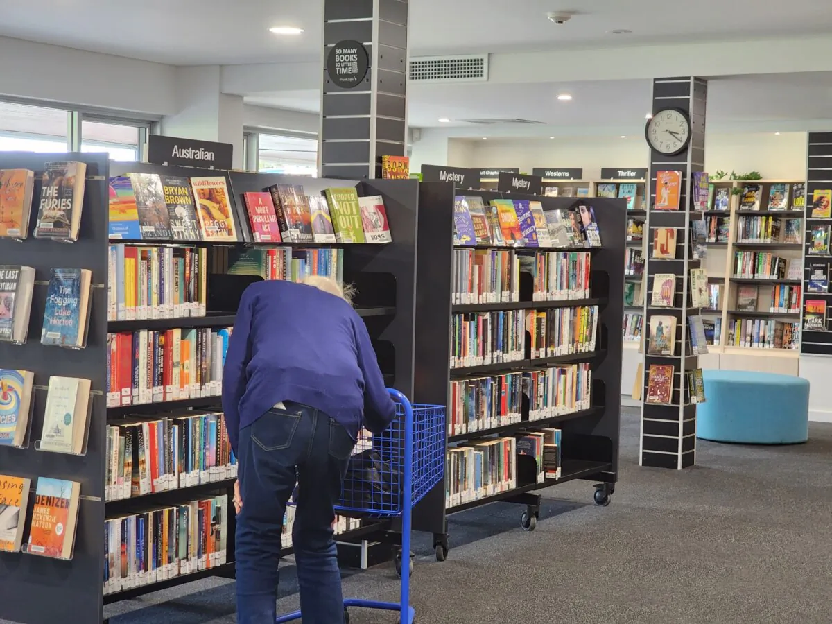An elderly woman looks at books on a shelf in a library in Albany, Western Australia, on April 22, 2024. (Susan Mortimer/The Epoch Times)