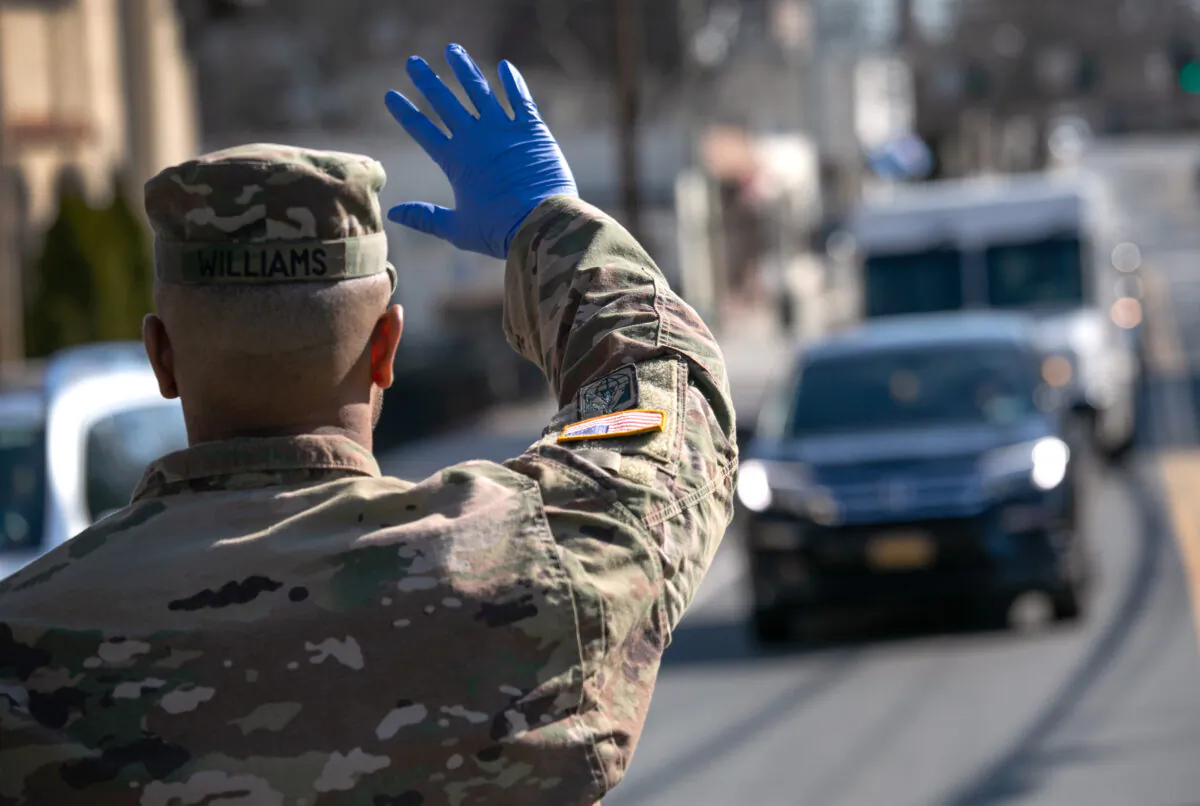 A U.S. National Guard soldier stops traffic as fellow troops distribute food to local residents at the WestCop community center in New Rochelle, New York on March 18, 2020. (John Moore/Getty Images)